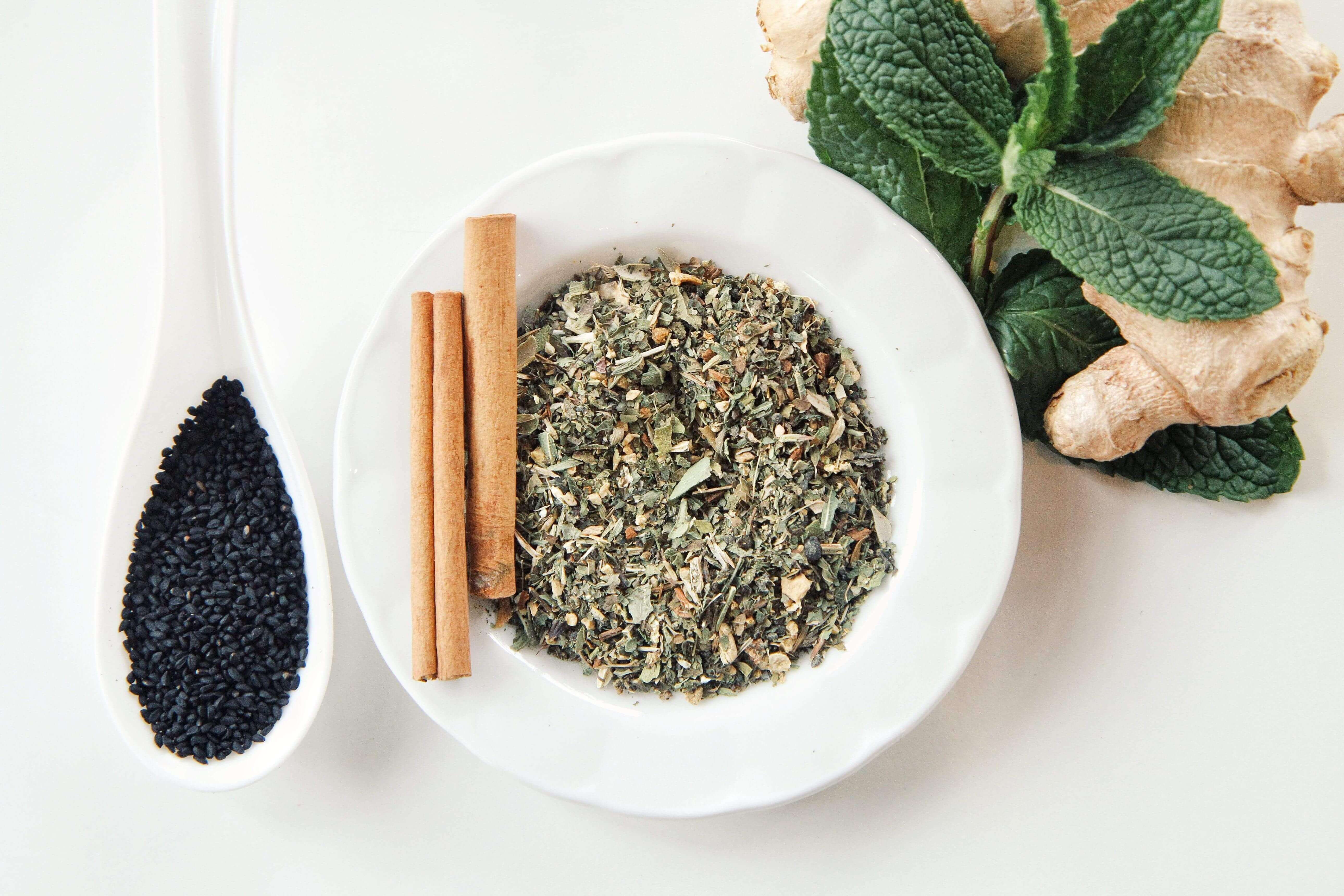 Botanical ingredients for a natural blood detox routine: black seed, cinnamon sticks, cloves, oregano and fresh peppermint