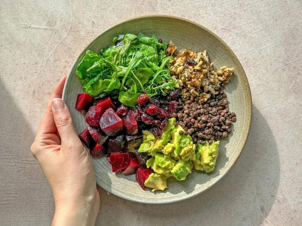 Overhead view of high-fibre foods including berries, spinach, kidney beans, oats and walnuts on a wooden table